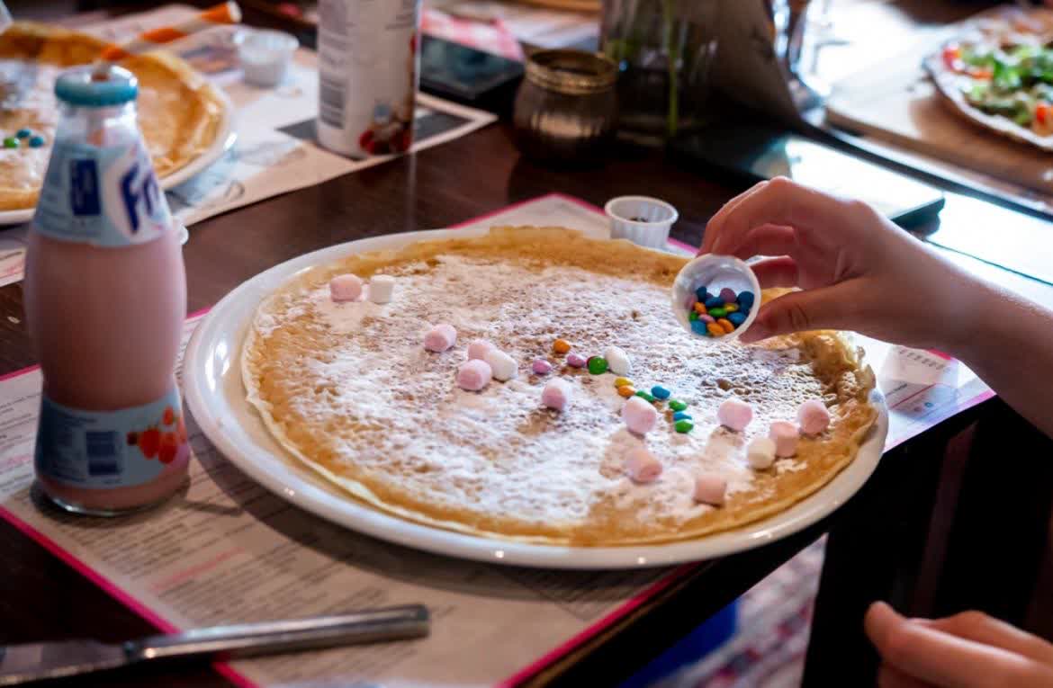 Kind versiert een pannenkoek